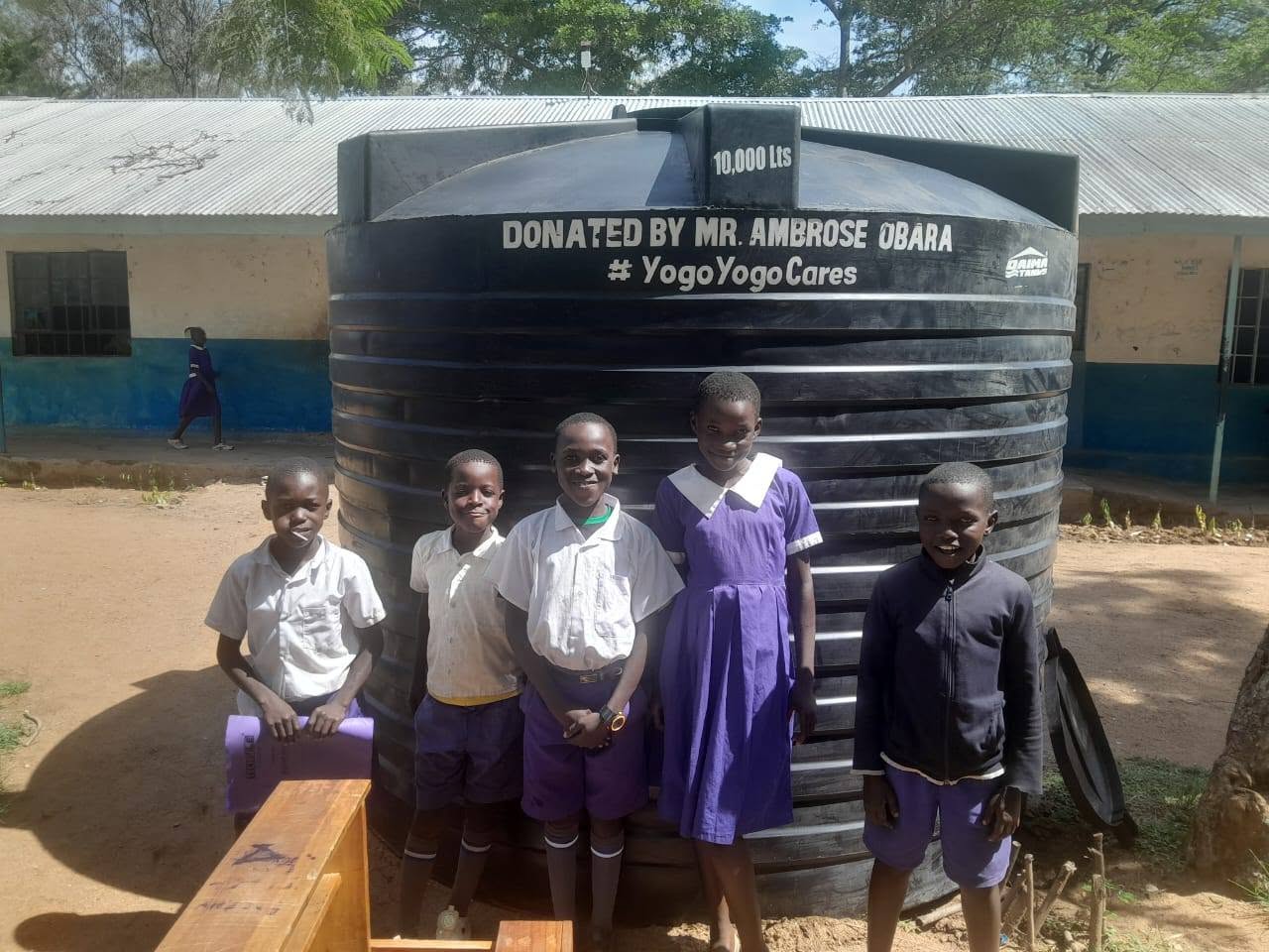 Pupils beside a donated 10,000-litre water tank